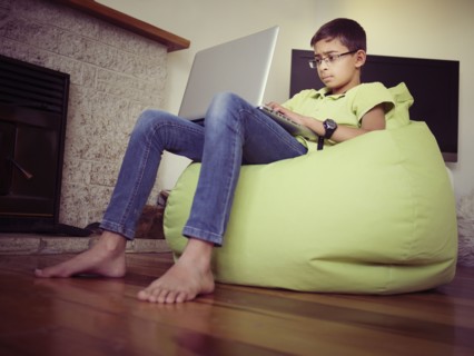 Mixed race boy using laptop in bean bag