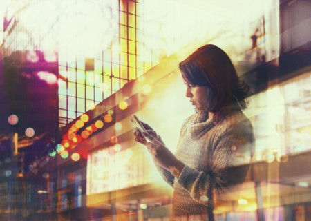 Woman using cell phone in city at night