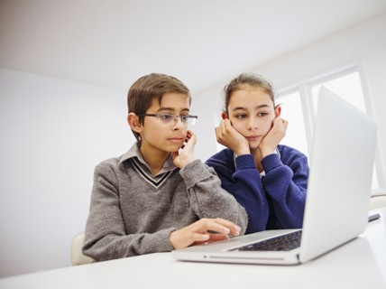 Mixed race children using laptop at desk
