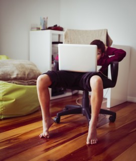 Mixed race boy using laptop in chair