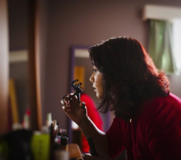 Mixed race woman curling her eyelashes