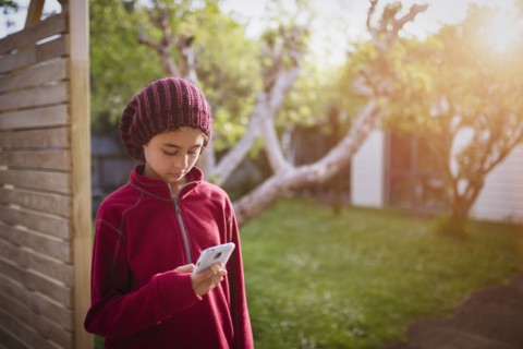 Mixed race girl using cell phone in backyard