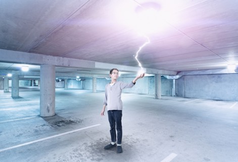 Mixed race boy holding lightning in parking lot