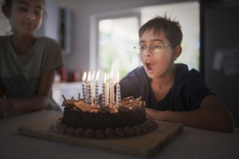 Mixed race boy blowing birthday candles