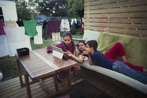 Mother and children using digital tablet in backyard