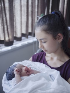Close up of girl holding newborn baby brother