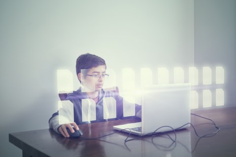 Mixed race boy using computer with holographic files