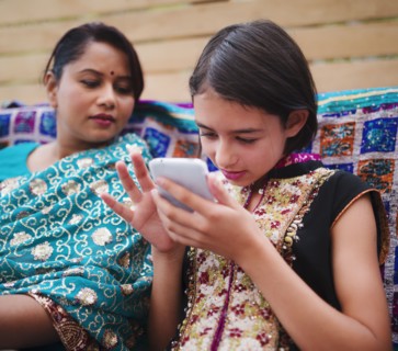 Mother and daughter in Indian clothing using cell phone
