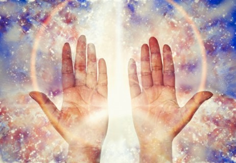 Close up of light glowing from hands of mixed race woman
