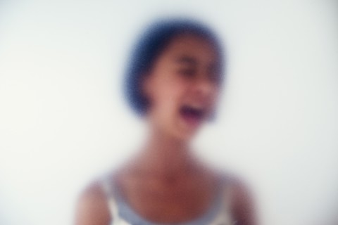 Mixed race girl shouting behind frosted glass