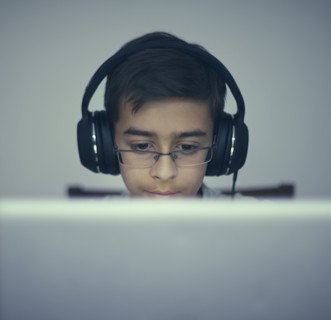 Mixed Race boy listening to laptop with headphones