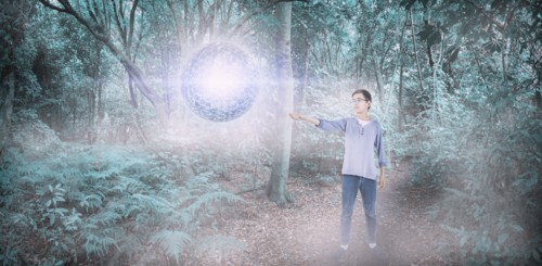 Mixed Race boy with floating sphere in forest