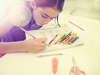 Mixed Race girl drawing faces in notebook