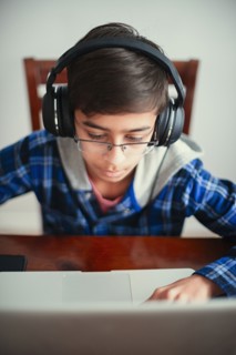 Mixed Race boy listening to laptop with headphones