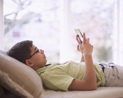 Mixed Race boy texting on cell phone near window