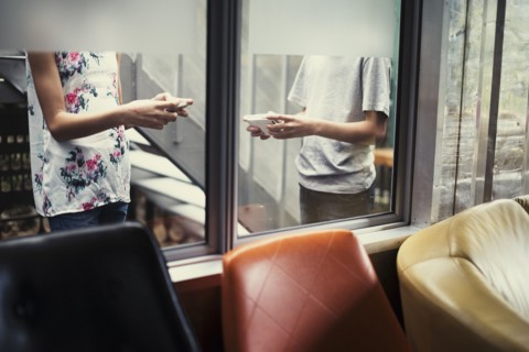 Mixed Race brother and sister texting on cell phones behind window