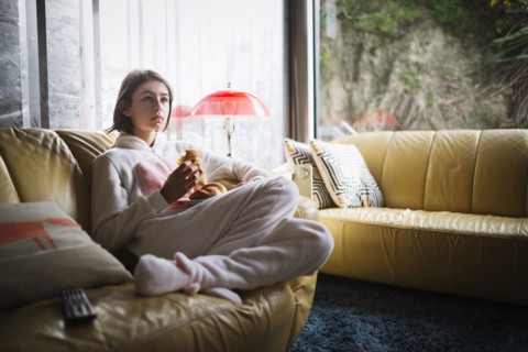 Mixed Race girl wearing rabbit costume sitting on sofa eating croissant