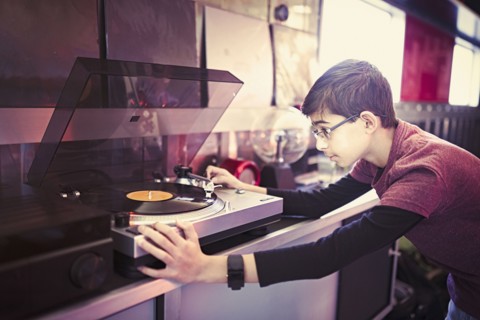Mixed Race boy playing vinyl record on turntable