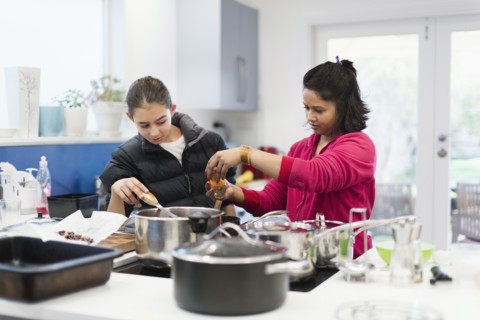Mother and daughter looking down at cooking food
