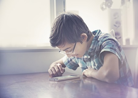 Smiling Mixed Race boy texting on cell phone