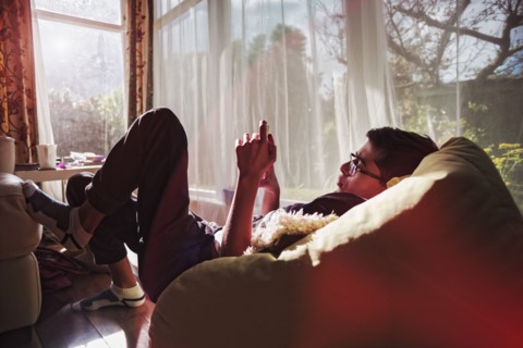 Mixed Race boy texting on cell phone near window