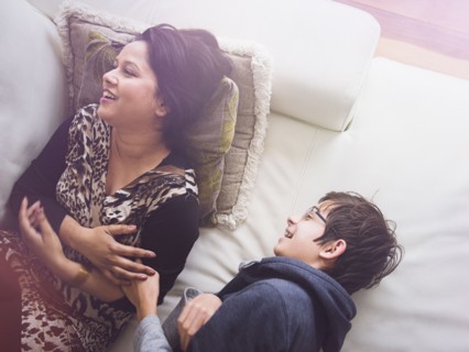 Mother and son laying on sofa and laughing