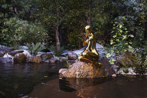 Pensive woman robot sitting on rock at river