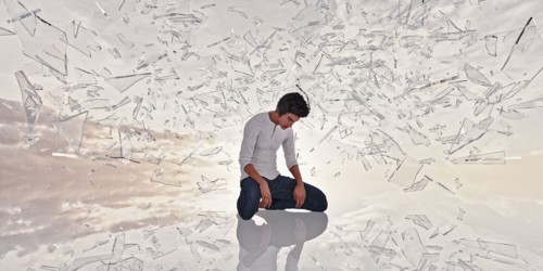 Shards of glass surrounding kneeling man