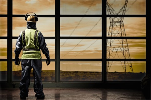 Hispanic construction worker looking out window at power lines