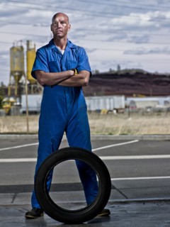 Serious mechanic standing with tire