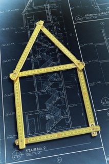 Rulers forming house over construction blueprints