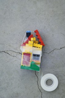 Plastic block house taped together on concrete