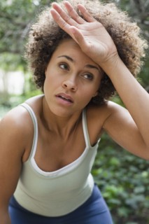 Mixed race woman wiping forehead