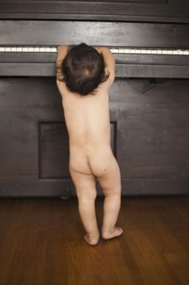 Naked mixed race baby playing piano