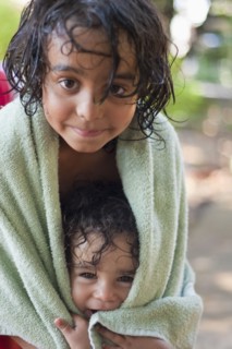 Wet mixed race boy and brother wrapped in towel