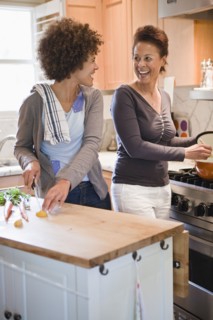 Mixed race mother and daughter cooking in kitchen