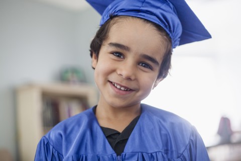 Smiling mixed race boy in graduation cap and gown