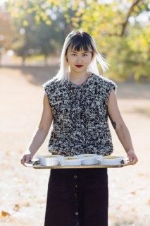 Asian woman holding platter of soup outdoors