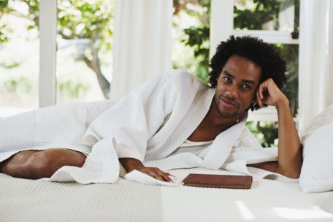Mixed race man laying on bed reading