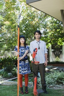 Couple working in garden with tree and weed trimmers