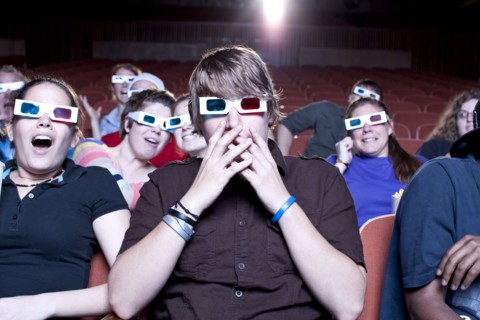 Friends watching movie in theater wearing 3D glasses