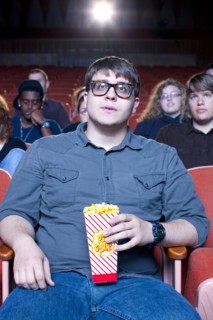 Caucasian man eating popcorn in movie theater