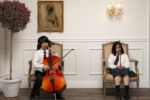 Vietnamese children with musical instruments sitting on elegant chairs