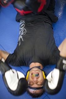 Caucasian boxer grimacing on mat