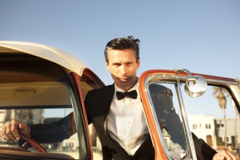 Caucasian man in tuxedo getting into car