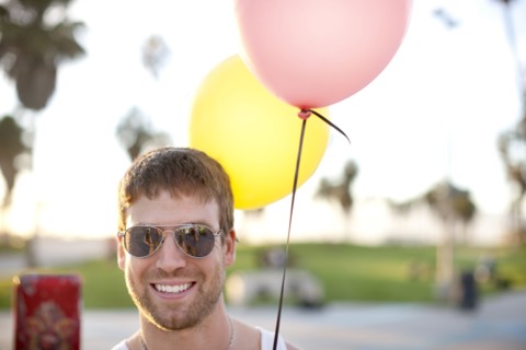 Caucasian man holding two balloons