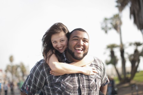 Grinning man giving wife piggyback ride