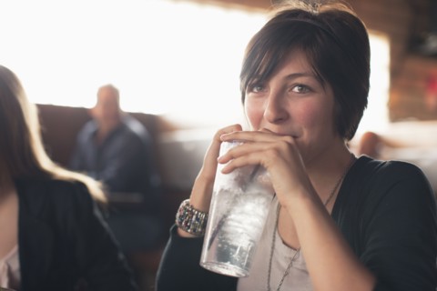 Caucasian teenager drinking water in restaurant