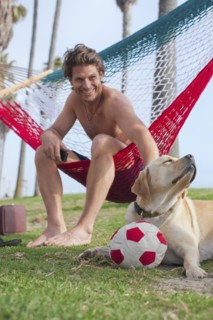 Caucasian man relaxing in hammock petting dog