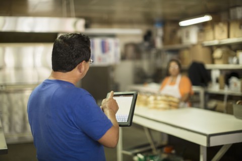 Hispanic baker using tablet computer in kitchen